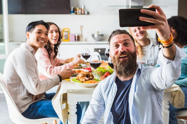 Ragazzi sorridenti che prendono un selfie di gruppo durante una cena