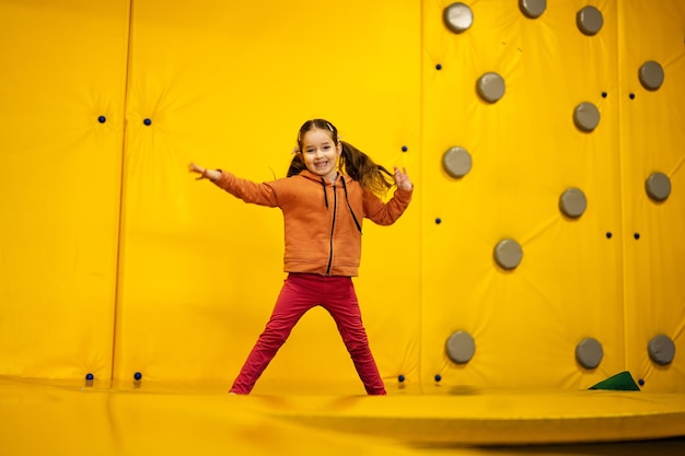 Ragazzina che salta sul trampolino al parco giochi giallo