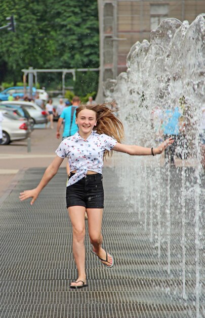 ragazzina che si diverte nelle fontane tempo estivo caldo in città