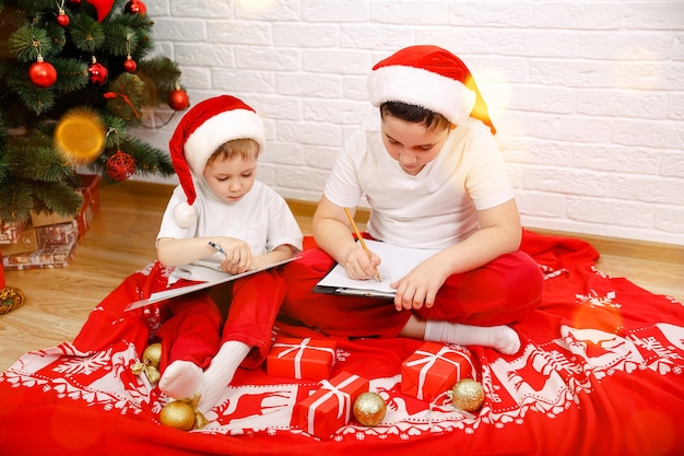 Ragazzini allegri a casa a Natale ragazzini che indossano il cappello di Natale