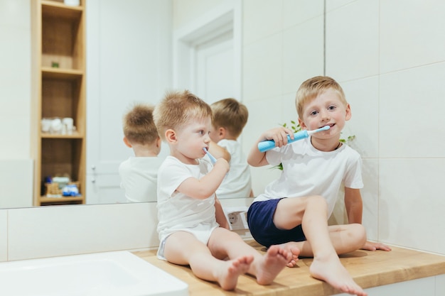 Ragazzini bambini che lavano i denti in bagno, due fratelli