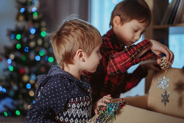 Ragazzini caucasici carini che decorano l'albero di Natale con decorazioni scintillanti