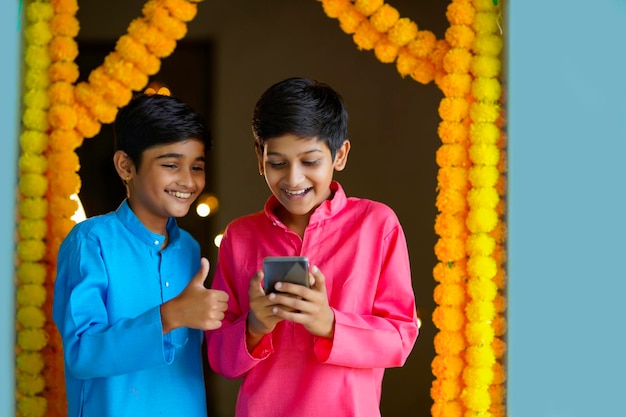 Ragazzini indiani che utilizzano smartphone e si godono il festival di diwali.