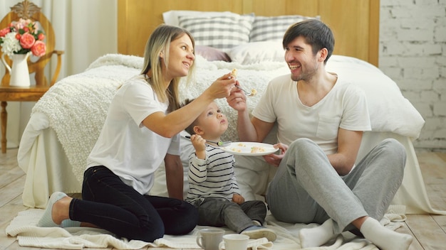 Ragazzino adorabile che festeggia il suo compleanno con padre e madre mangiano la torta in camera da letto