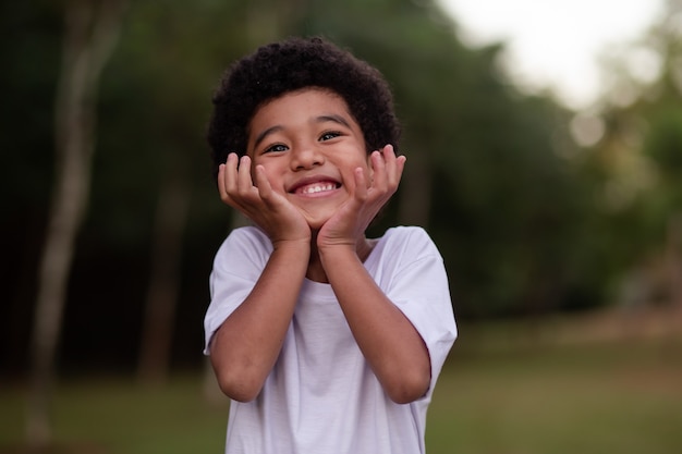 Ragazzino afro che sorride alla telecamera nel parco