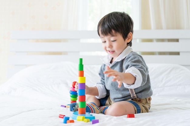 Ragazzino allegro con il giocattolo d'apprendimento di legno variopinto