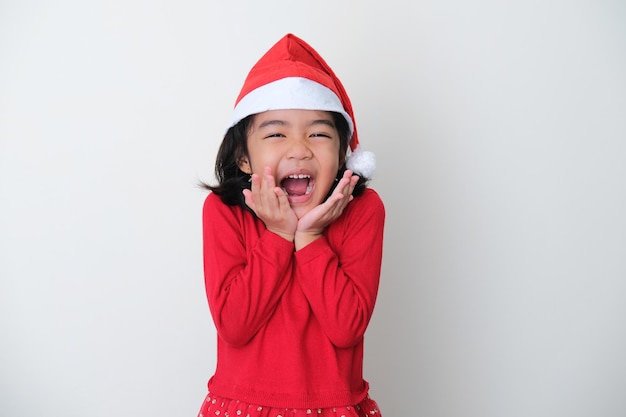 Ragazzino asiatico che indossa il cappello di Natale che mostra l'espressione del viso felice