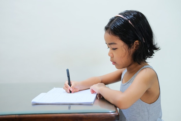 Ragazzino asiatico che studia a tavola con un'espressione seria