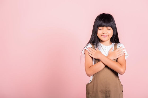 Ragazzino asiatico di 10 anni che fa gesto di gratitudine e occhi chiusi