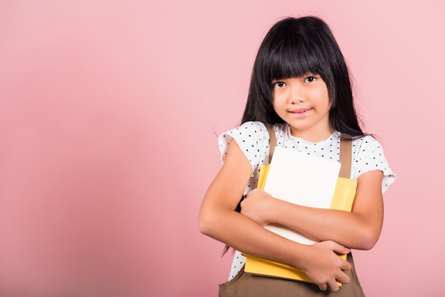 Ragazzino asiatico di 10 anni che tiene il libro per andare a scuola