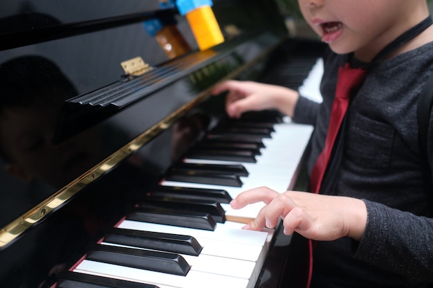 Ragazzino asiatico ragazzino suonare il pianoforte nel soggiorno di casa