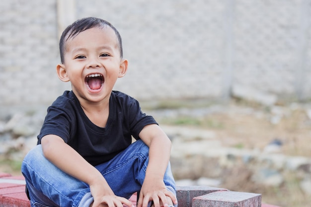 Ragazzino asiatico sveglio sorridente e allegro che gioca all'aperto