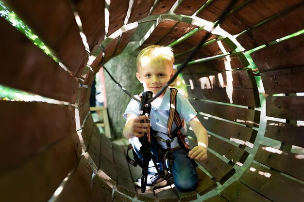 Ragazzino attivo che si arrampica su una corda sulla strada per il parco divertimenti in estate