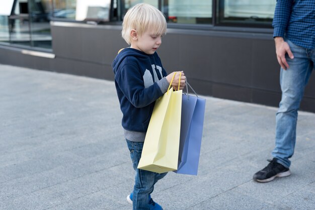 Ragazzino biondo con borse della spesa. Shopping in famiglia