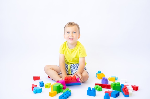 Ragazzino carino, bambino gioca con un costruttore, si basa su uno sfondo bianco, isolato