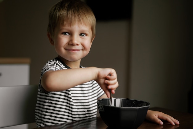 Ragazzino carino che mangia i fiocchi d'avena per la colazione