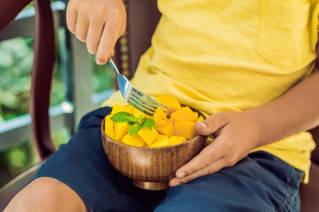 Ragazzino carino che mangia mango sulla terrazza