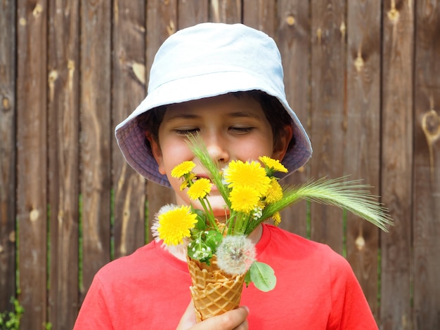 Ragazzino carino con bouquet di denti di leone gialli