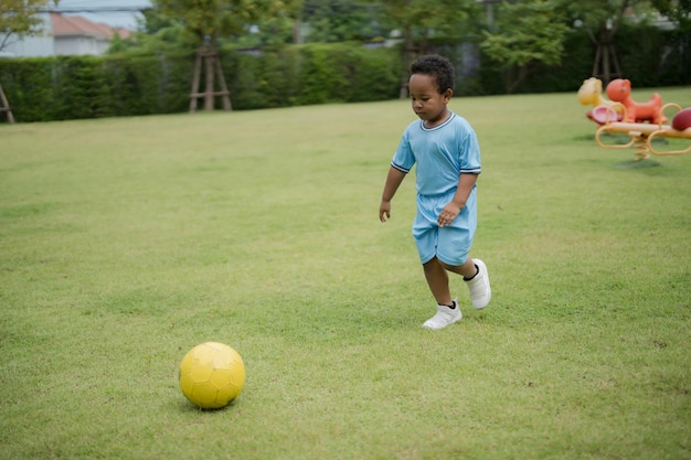 Ragazzino carino con pallone da calcio nel parco in una giornata di sole