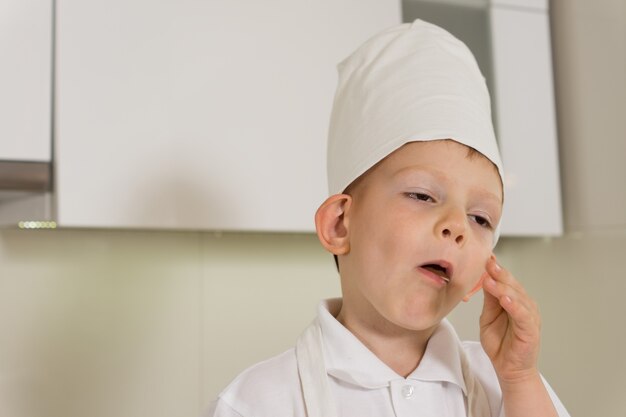 Ragazzino carino con un cappello o un cappello da chef