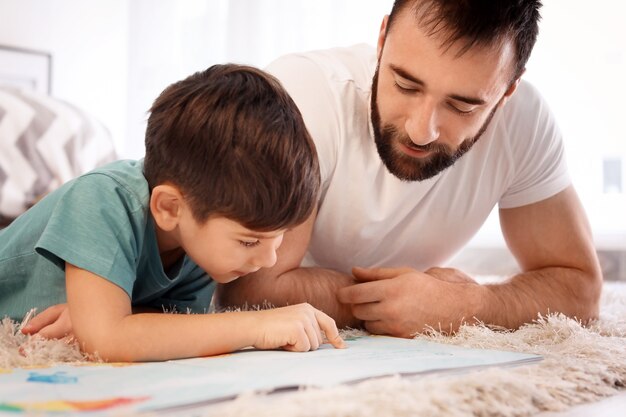 Ragazzino carino e suo padre che leggono un libro a casa