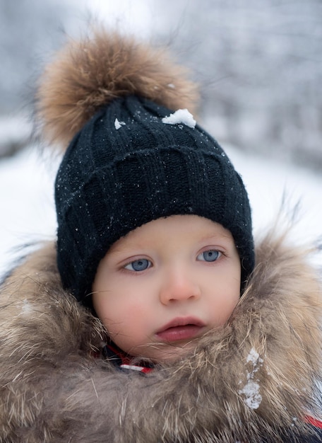 Ragazzino carino in abiti invernali ragazzino in abiti invernali che cammina sotto la neve ragazzino carino portr...