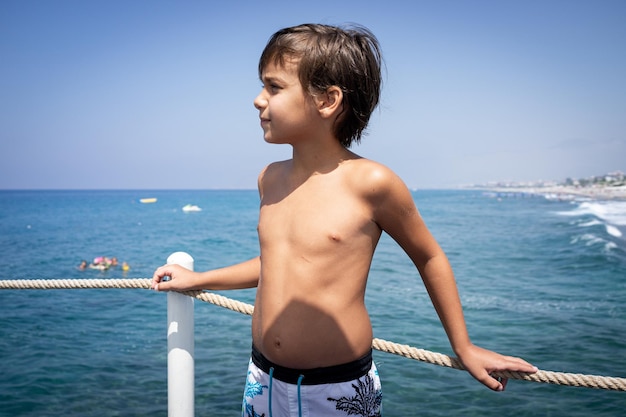 Ragazzino carino sul molo sul mare che si gode la vacanza