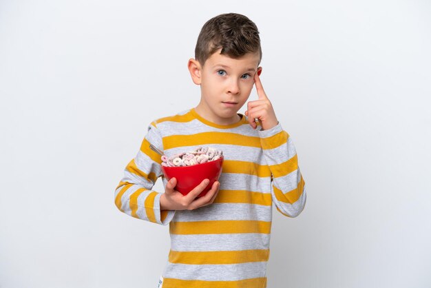 Ragazzino caucasico che tiene una ciotola di cereali isolata su sfondo bianco pensando a un'idea