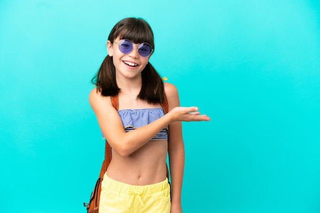 Ragazzino caucasico che va in spiaggia isolato su sfondo blu che presenta un'idea mentre guarda sorridendo verso