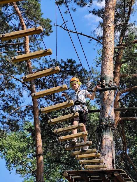 Ragazzino che attraversa un ponte di legno in un parco giochi