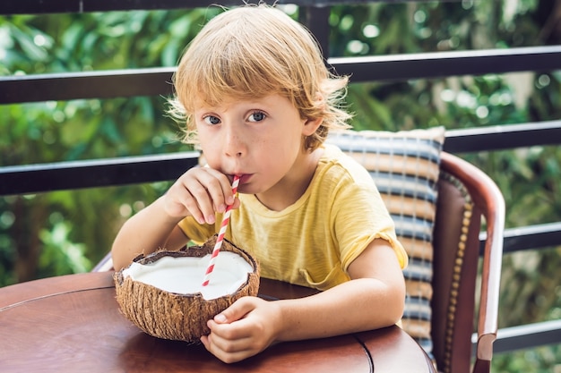 Ragazzino che beve latte di cocco da metà della noce di cocco