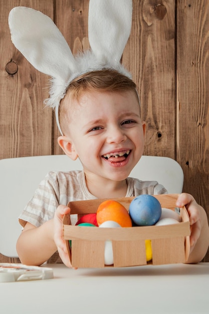 Ragazzino che dipinge le uova variopinte per pasqua su fondo di legno