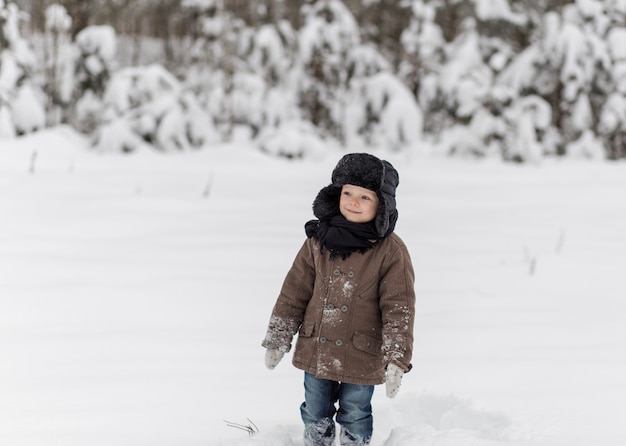 ragazzino che gioca a palle di neve in inverno in natura