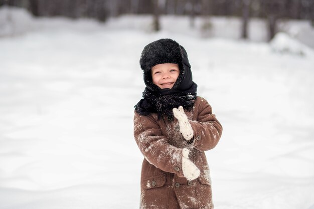 ragazzino che gioca a palle di neve in inverno in natura