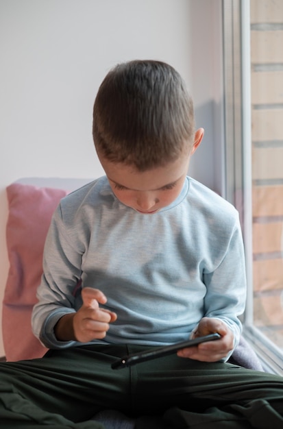 Ragazzino che gioca al gioco mobile su smartphone seduto su un divano vista dall'alto Tempo libero per bambini a casa video