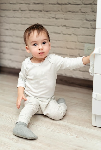 Ragazzino che gioca sul pavimento Bambino seduto sul pavimento