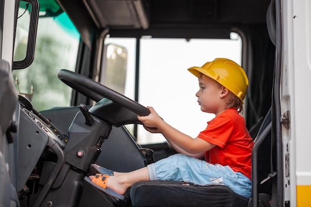 Ragazzino che guida il trattore Il figlio aiuta il padre a riparare il trattore Coinvolgere il bambino nel lavoro