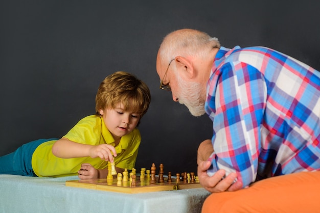 Ragazzino che impara a giocare a scacchi e attività per bambini nonno e nipote che giocano