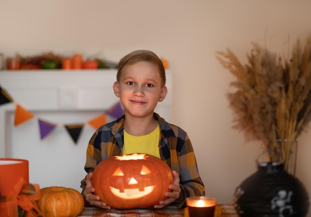 Ragazzino che intaglia le tradizionali lanterne di Halloween con la faccia spaventosa per la festa a casa.