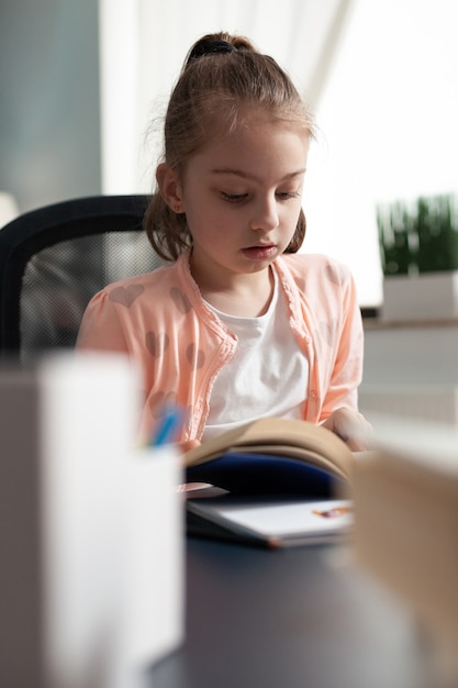 Ragazzino che legge il libro di scuola per la scadenza dei compiti