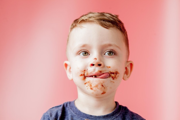 Ragazzino che mangia cioccolato Carino ragazzo felice spalmato di cioccolato intorno alla bocca Concetto di bambino