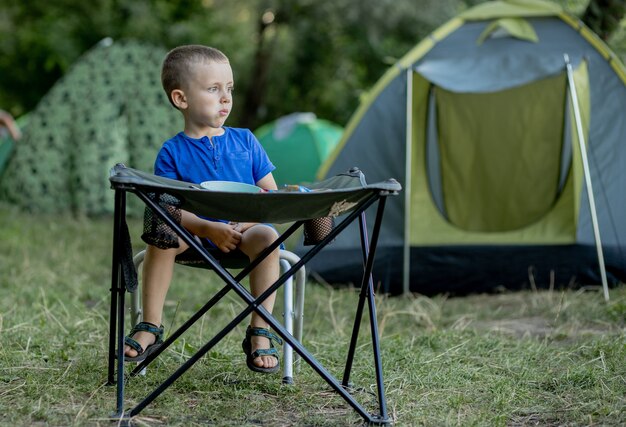 Ragazzino che mangia colazione all'aperto al campeggio