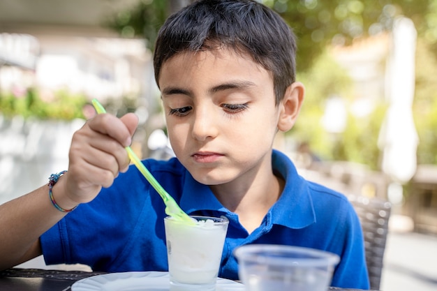 Ragazzino che mangia il gelato al bar all'aperto in una giornata di sole