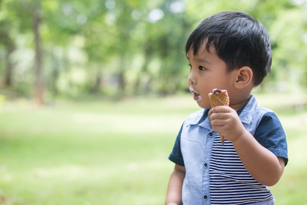 Ragazzino che mangia il gelato al campo da giuoco con tempo felice.