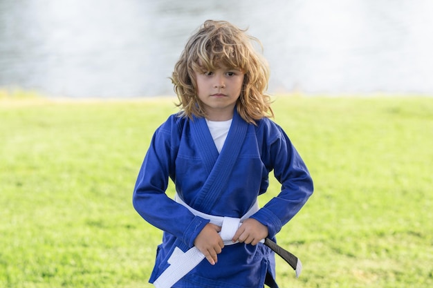 Ragazzino che pratica karate sport all'aperto bambini karate ragazzino che indossa kimono facendo karate nel parco l