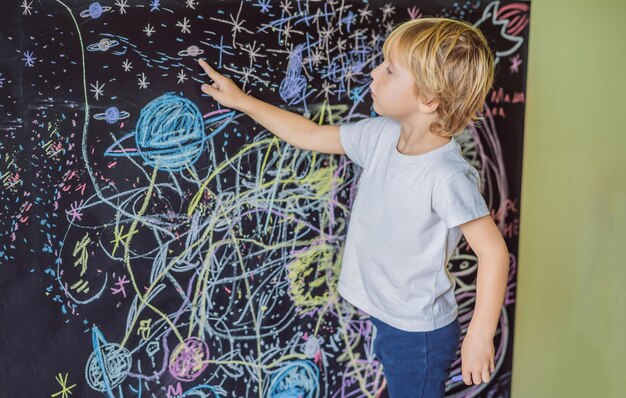 Ragazzino che punta i pianeti spaziali e le stelle sul muro