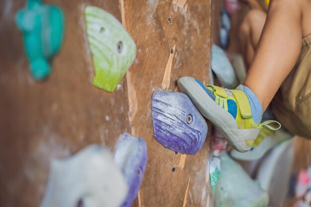 Ragazzino che si arrampica su una parete rocciosa con stivali speciali per interni