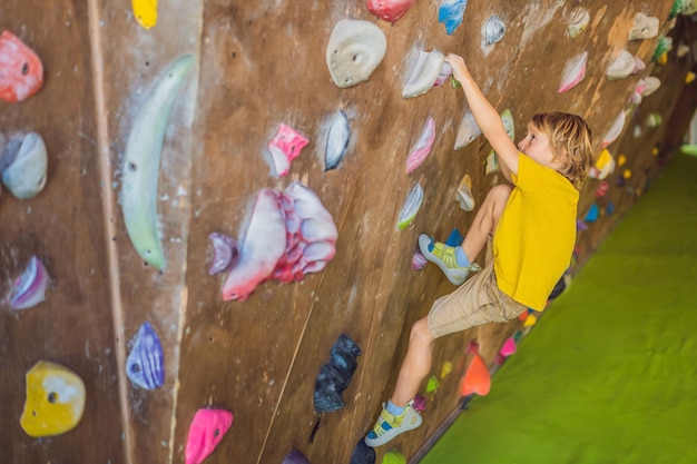 Ragazzino che si arrampica su una parete rocciosa con stivali speciali per interni