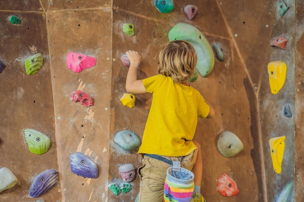 Ragazzino che si arrampica su una parete rocciosa con stivali speciali per interni