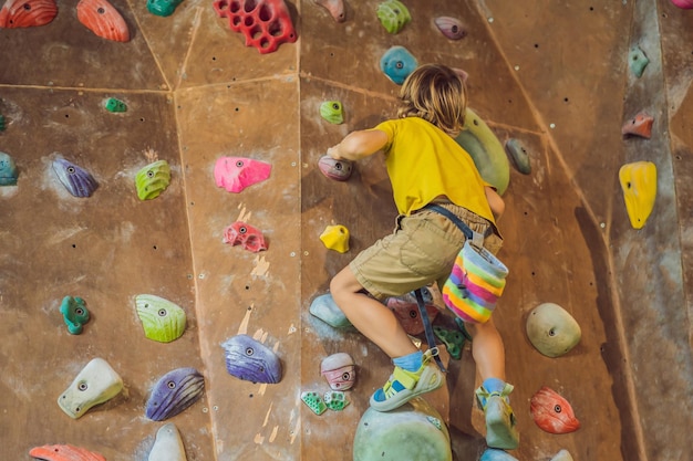 Ragazzino che si arrampica su una parete rocciosa con stivali speciali per interni